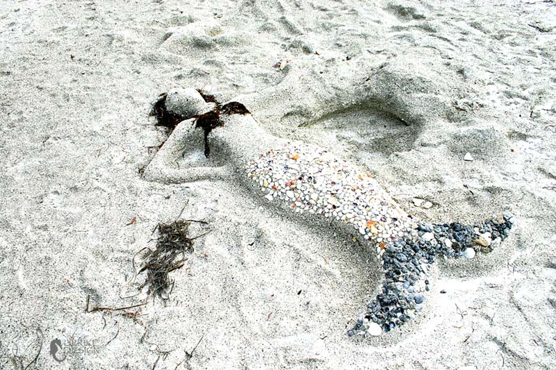 A mermaid sleeping on the sand.